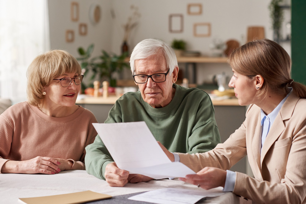 Pareja de la tercera edad consultando con una especialista en trámites de herencias